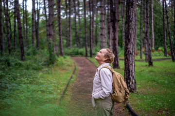 Naklejka na ściany i meble Beautiful happy caucasian active senior woman enjoying nature in autumn park. Active pensioners lifestyle concept