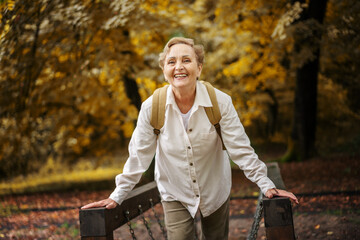 Beautiful happy caucasian active senior woman enjoying nature walking in autumn park. Active pensioners lifestyle concept