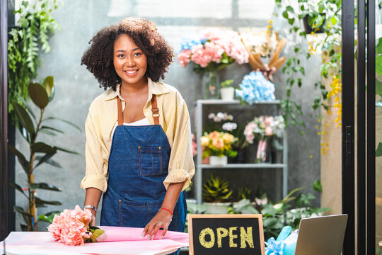 African American womanlogger influencer or SME owner people smile work on home video camera selfie shoot.Smiling female florist talking on mobile. Young woman working at flower shop with Open sign.