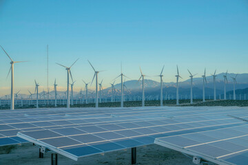 Solar panels and wind turbines against the sunset sky on a desert in California