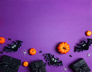 Halloween purple background with black gift, pumpkins, bats and spiders.