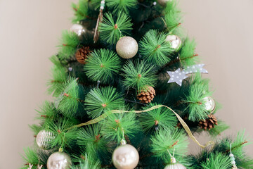 Christmas tree decorated with Christmas balls, Christmas stars, dried pine cones and a bow on a beige background