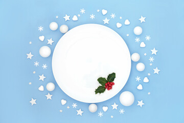 Fototapeta na wymiar Christmas dinner plate table place setting with holly red berries and white frosted decorations. Abstract minimal design for Xmas festive holiday season and New Year. On pastel blue.