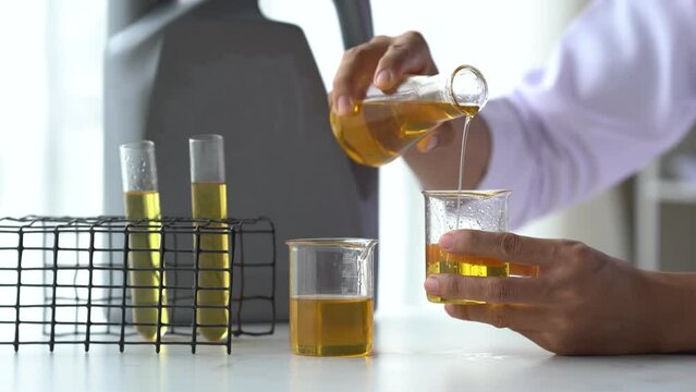 Close up lap worker test and pours car engine oil quality test, checking and compare color difference.