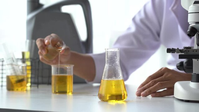 Close up lap worker test and pours car engine oil quality test, checking and compare color difference.