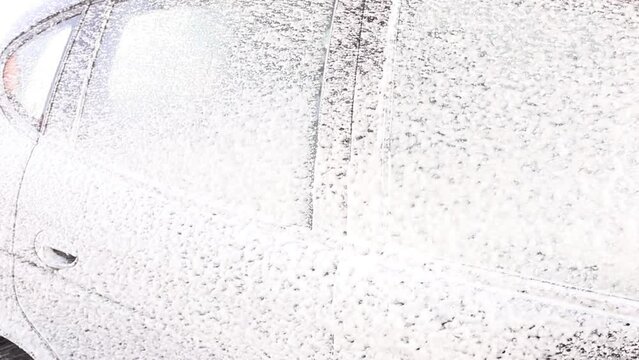 someone washes a car with foam at a car wash
