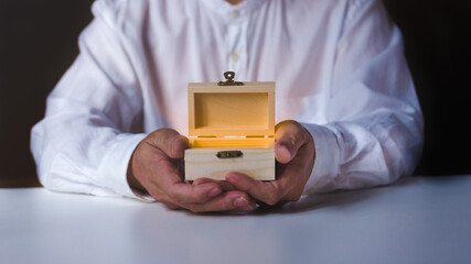 Man hand holding open wooden box on white table.