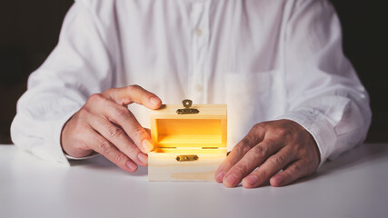 Man hand holding open wooden box on white table.