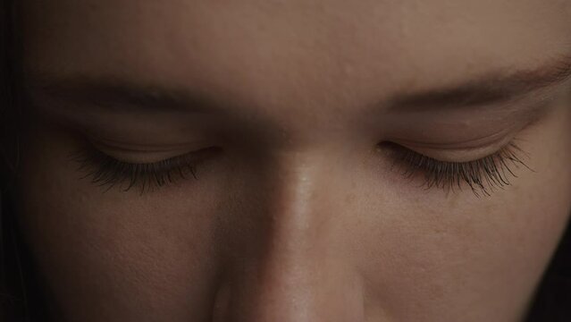 Close up of a caucasian woman raising up her head and open her eyes in slow motion
