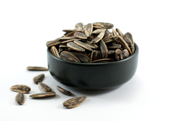 Black ceramic cup of sunflower seeds isolated on white background.