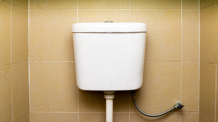 The center view of white toilet cistern, a flush mechanism in a room.