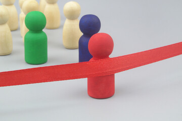 Colored and common wooden people figures as competitors and red finish line ribbon on gray background. 