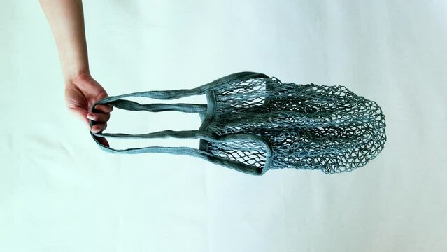 Hand with eco friendly string bag on white background