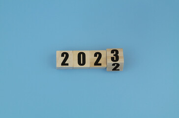 Wooden cubes with numbers 2023 and 2022 on blue. Flipping of 2022 to 2023.  