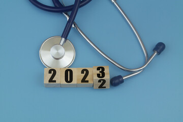 Changes in health care in year 2023. Stethoscope and numbers 2022 and 2023 on wooden cubes on blue...