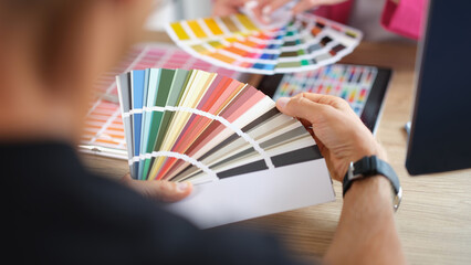 Hands of designers during the discussion and selection of colors for interior in studio