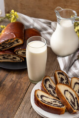 Roll with poppy seeds and a glass of milk. Food on the table. Sweet sweet pastries. Homemade simple yeast bun with filling. Breakfast on a wooden table. lactose and gluten. Honey spas
