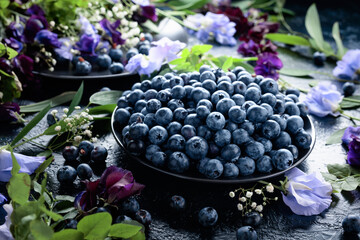Fresh blueberries on a black plate.