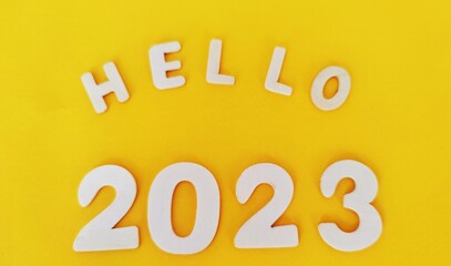 The word 2023 is made of wooden numbers on a yellow background.  Happy New Year.  New year and holiday concept