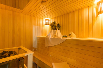 The interior of a wooden sauna with a heating element and bath accessories on a bench.