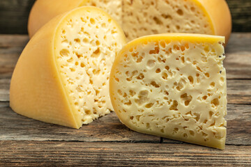 close up french hard cheese with holes emmentaler on a wooden background. farmer market. place for...