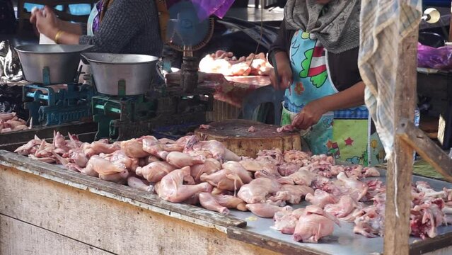 The activities of traders or sellers and buyers of broiler chickens in traditional markets. Chicken traders and sellers are slaughtering raw chicken in a traditional market.