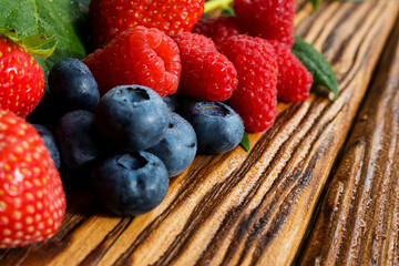 Berries on a wooden background. Summer or spring Organic berry. Strawberries, Raspberries, Blueberries. Agriculture, Gardening, Harvesting Concept.