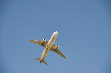 Landscape of airplane flying at low altitude at low angle, with blue sky background and clear of sunny day.