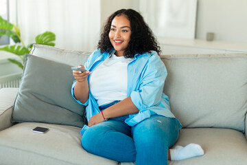 Smiling African American Female Watching TV Switching Channels At Home