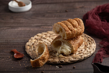 Puff pastry bun with sesame and condensed milk, homemade cakes and sweets, pastries for tea on a wooden background, valavan with condensed milk, coffee and pastries, bread products