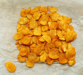 Top view potato chips with paprika on paper.