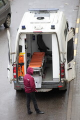 A paramedic near an ambulance car with an empty gurney. Top view