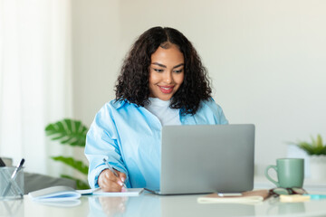 Black Businesswoman Using Laptop Computer Taking Notes Sitting In Office