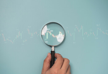 Trader hand holding magnifier glass with bar graph with increasing arrow for analysis technical graph of stock market chart , Business investment concept.