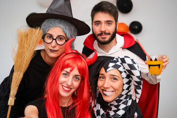 Four people taking a selfie photo at a costume Halloween party in a house.