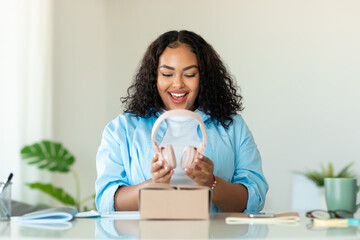 Happy African American Lady Holding Headphones Unpacking Box In Office