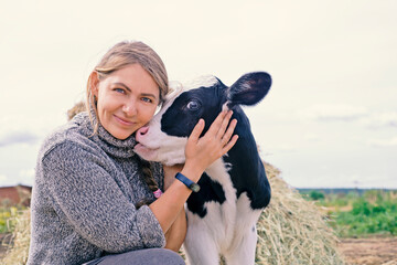 pretty black-white new born calf posing with farmer. close up