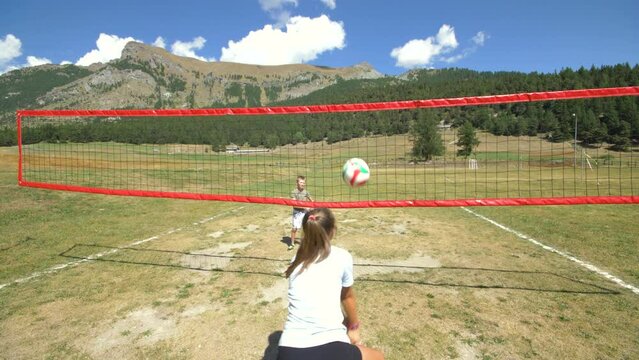 Two children are playing volleyball in the mountain