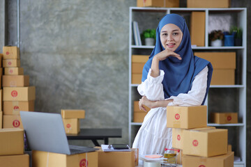 Portrait of a young Muslim woman, a small start-up business owner who works with parcel boxes in her home office.