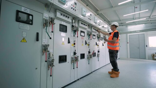Electrical engineer working check the electric current voltage and overload at front of load center cabinet or consumer unit for maintenance in main power distribution system room.