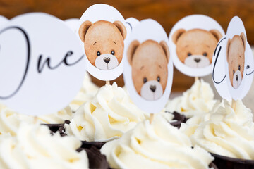 close up cupcakes with white cream and toppers with bears and text one