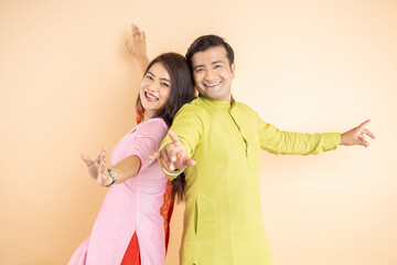 Happy indian couple dancing together wearing traditional or ethnic cloths isolated on studio background, Man and woman celebrating diwali festival, online shopping deal, enjoying life concept,