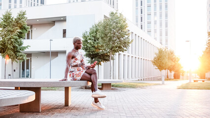 Black androgynous man using smartphone on street
