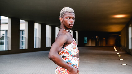 Confident black transsexual guy in dress looking at camera on street