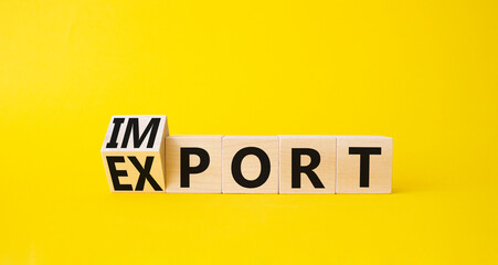 Import and Export symbol. Turned wooden cubes with words Export and Import. Beautiful yellow background. Business concept. Copy space.