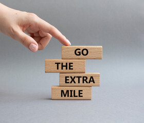 Go the extra mile symbol. Wooden blocks with words Go the extra mile. Beautiful grey background. Businessman hand. Business and Go the extra mile concept. Copy space.