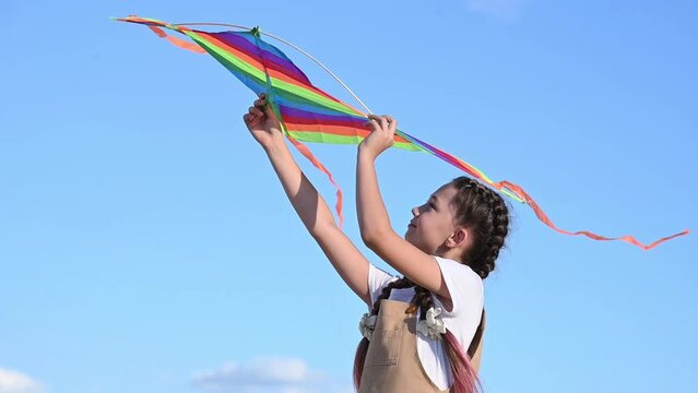 The girl alone launches a multicolored kite into the sky.