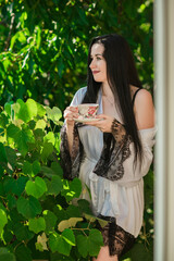 Femininity sexy woman on a balcony with a cup of tea, concept of tenderness and ladies sensuality