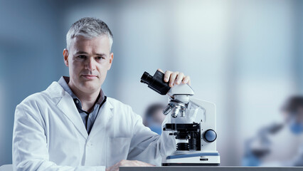 Medical scientist posing with a microscope