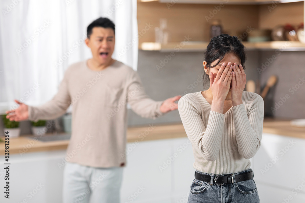 Wall mural emotional asian husband and wife having fight at kitchen